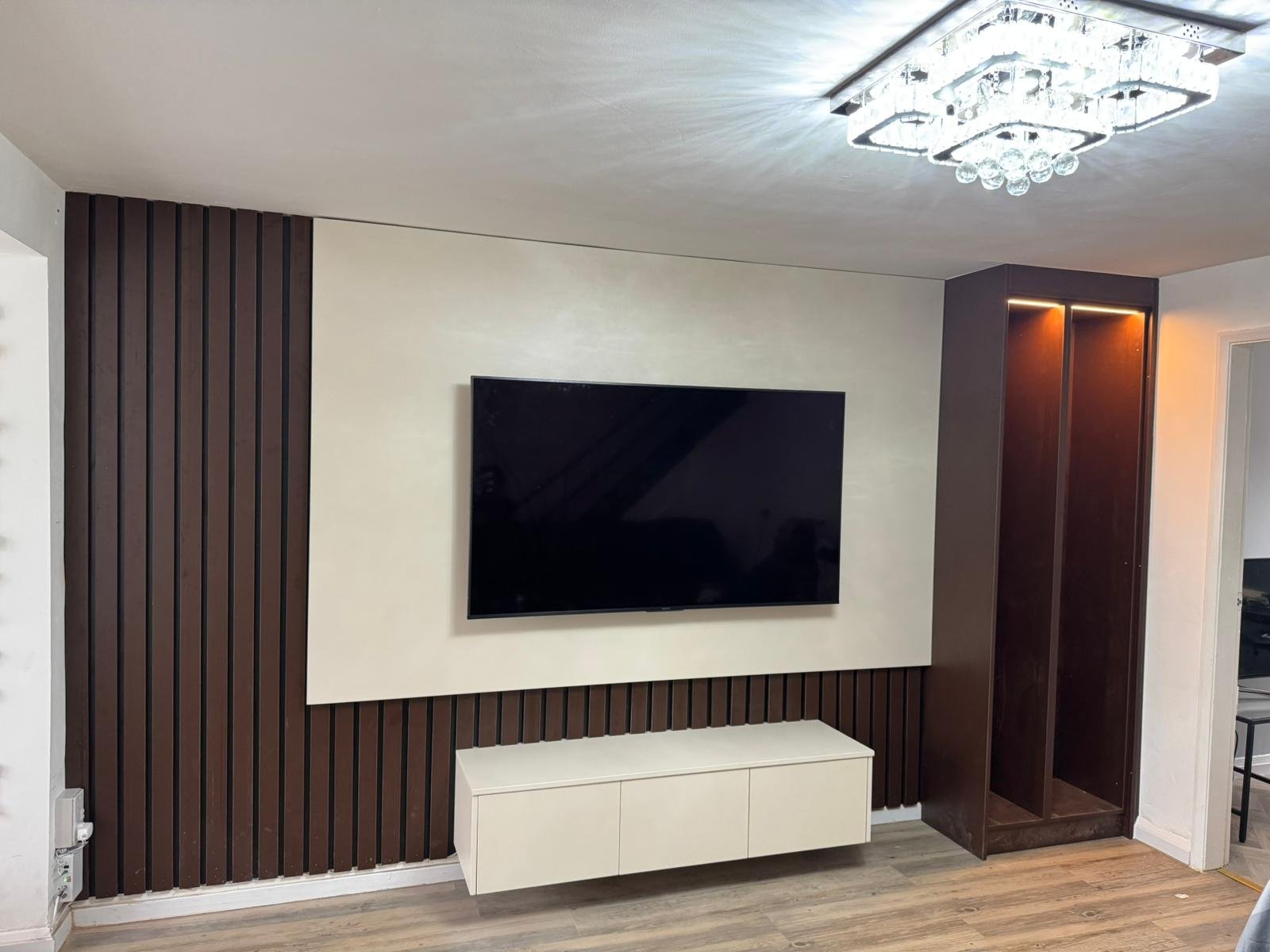 Dark timber slat media wall with painted centre panel and floating cabinet