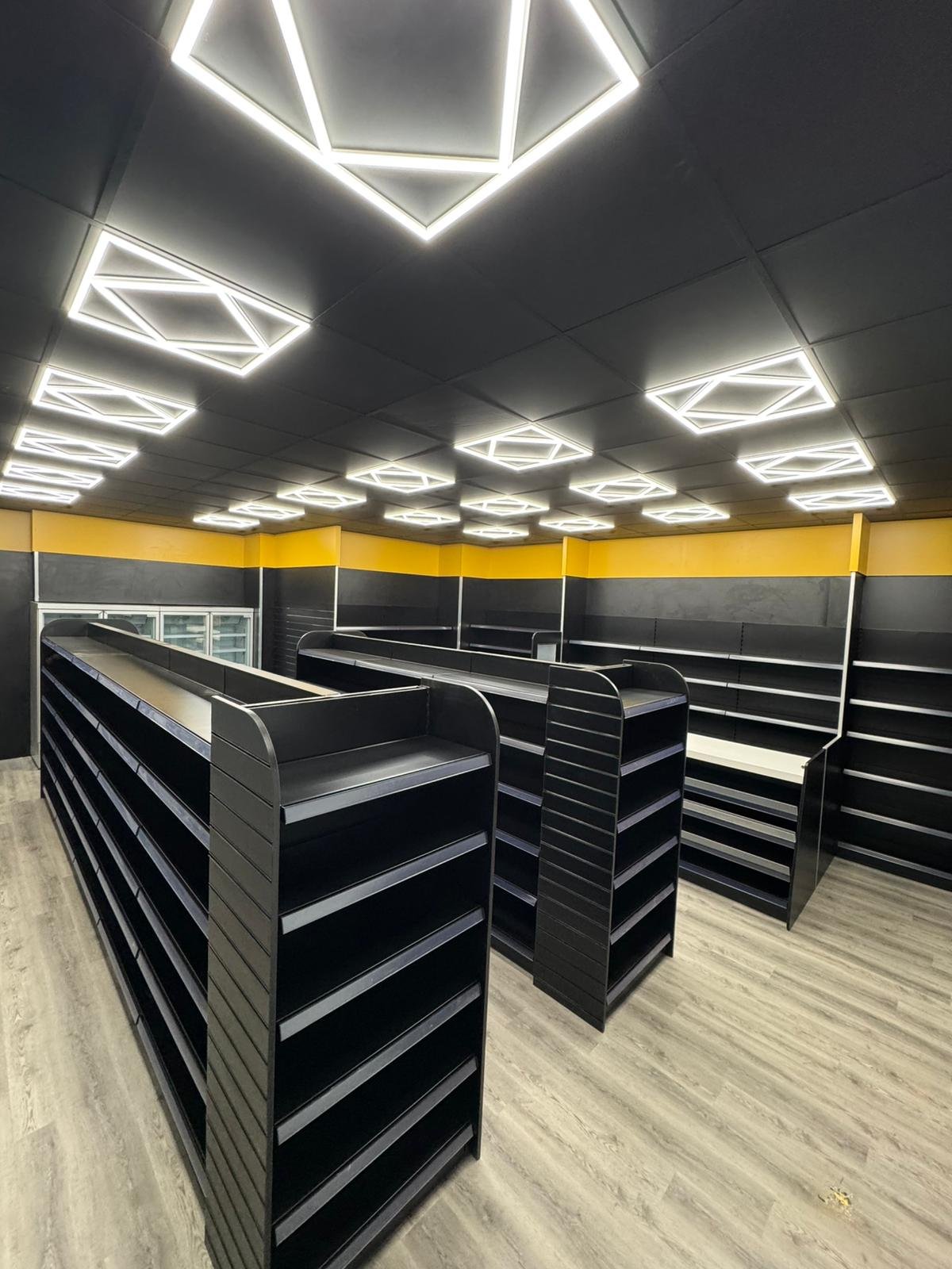 Retail store aisles with black shelving and yellow wall accents